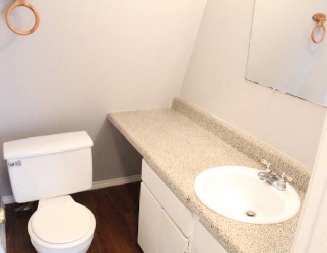 bathroom with hardwood / wood-style floors, vanity with extensive cabinet space, and toilet