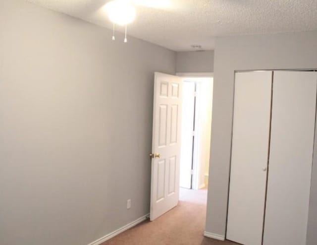 unfurnished bedroom with carpet, a closet, and a textured ceiling