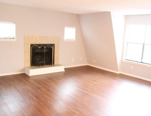 unfurnished living room with dark wood-type flooring and a tile fireplace