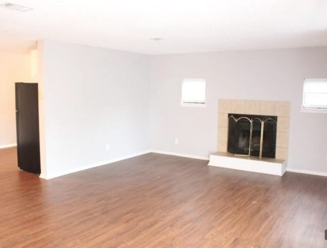 unfurnished living room featuring dark hardwood / wood-style floors and a tile fireplace