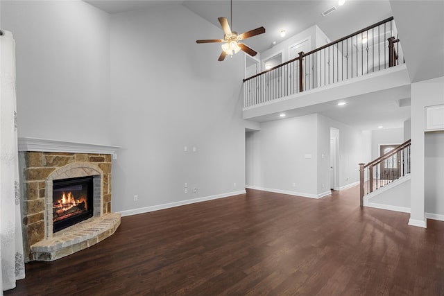 unfurnished living room featuring dark hardwood / wood-style floors, high vaulted ceiling, ceiling fan, and a stone fireplace