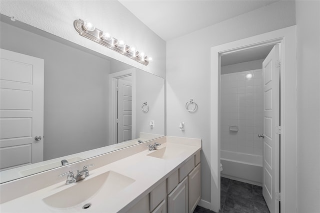 full bathroom with vanity with extensive cabinet space, tiled shower / bath, double sink, tile flooring, and toilet