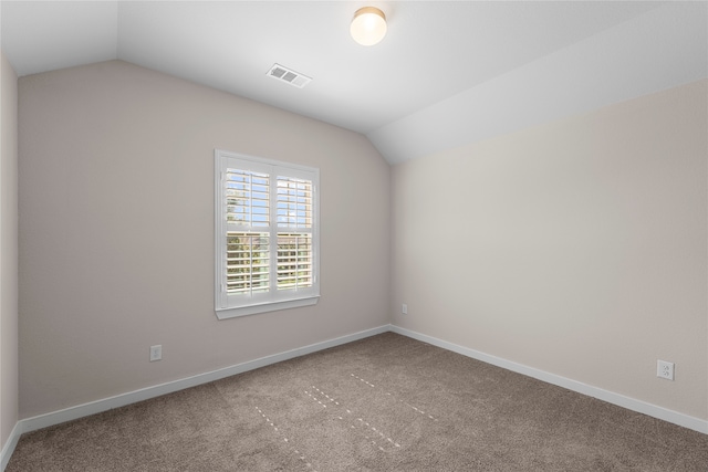 carpeted spare room with vaulted ceiling