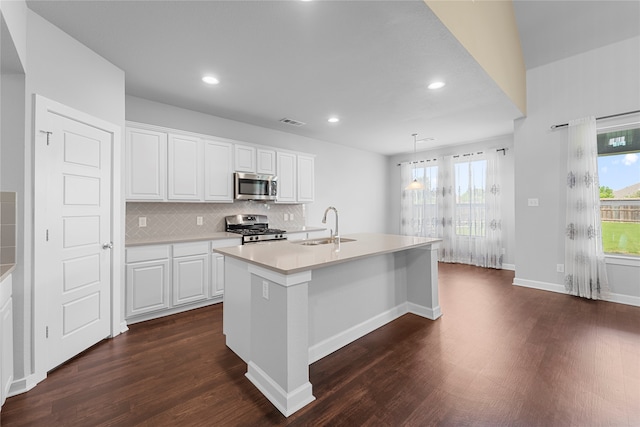 kitchen featuring appliances with stainless steel finishes, sink, white cabinetry, dark hardwood / wood-style floors, and a center island with sink