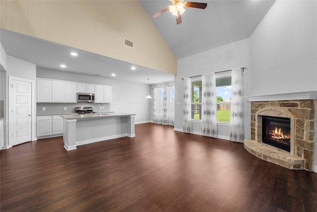 unfurnished living room with high vaulted ceiling, dark wood-type flooring, ceiling fan, and a fireplace