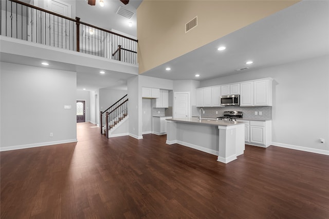 kitchen featuring white cabinetry, stove, dark hardwood / wood-style floors, and a center island with sink