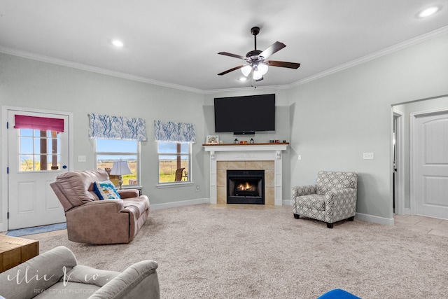 living room featuring a tile fireplace, ceiling fan, light carpet, and ornamental molding