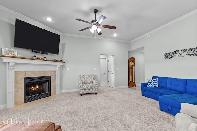 carpeted living room with ceiling fan, crown molding, and a tile fireplace