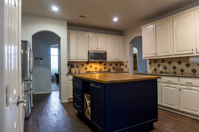 kitchen with white cabinets, a kitchen island, backsplash, and stainless steel appliances