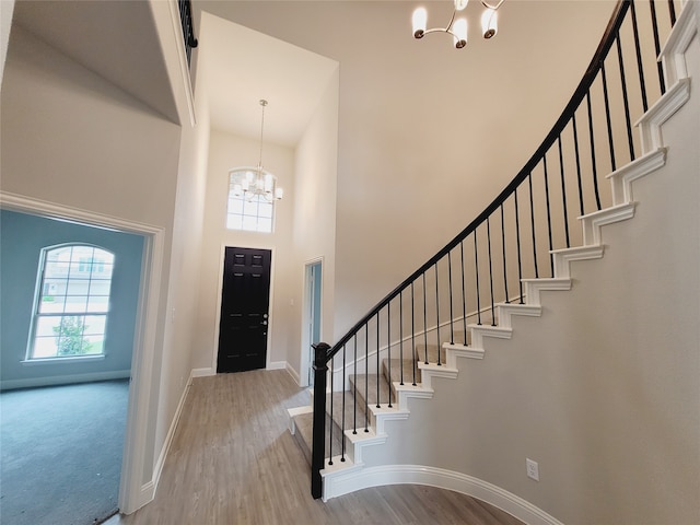 foyer entrance featuring a chandelier, carpet, and a towering ceiling