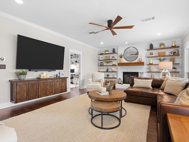 living room featuring ceiling fan, dark wood-type flooring, crown molding, and a brick fireplace