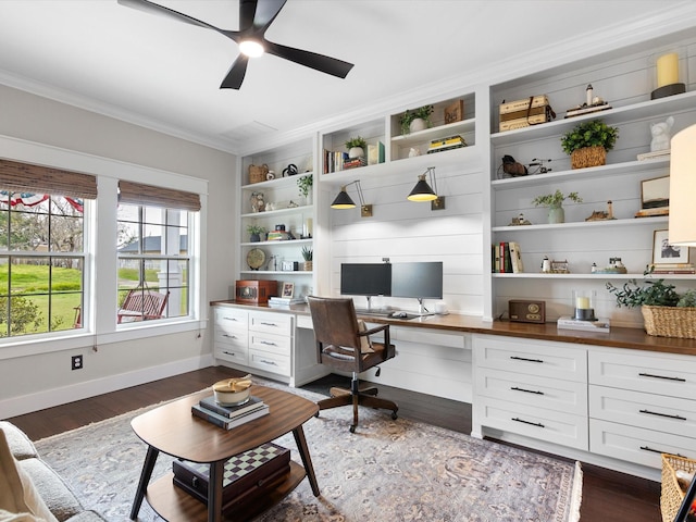 office featuring crown molding, built in desk, dark wood-type flooring, ceiling fan, and built in features