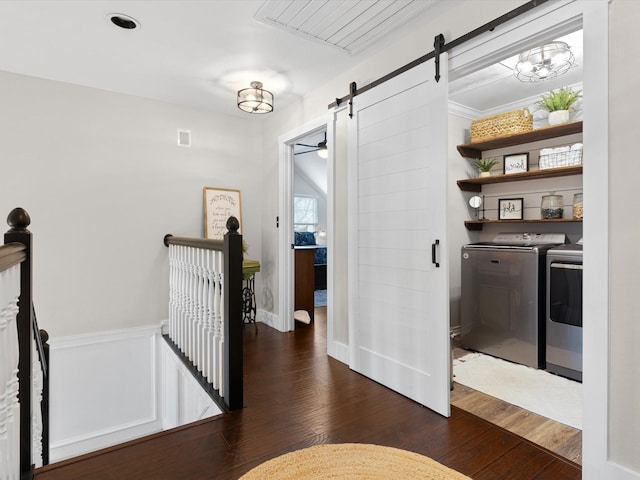 hallway with a barn door, dark hardwood / wood-style floors, and washing machine and clothes dryer