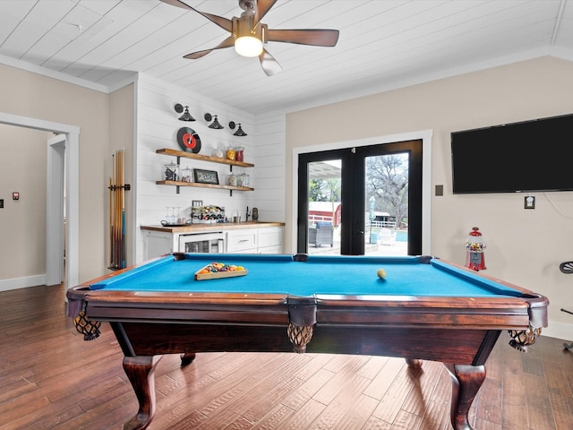 recreation room with dark wood-type flooring, french doors, ceiling fan, bar, and ornamental molding