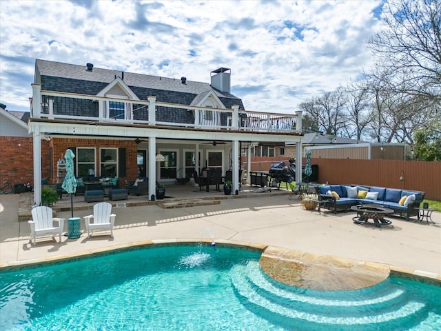 rear view of house featuring a patio area, a fenced in pool, and an outdoor living space with a fire pit