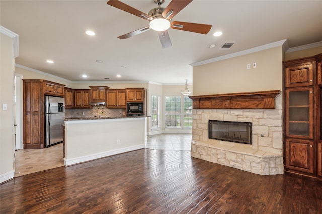 kitchen with stainless steel fridge with ice dispenser, hardwood / wood-style flooring, ceiling fan, and a stone fireplace