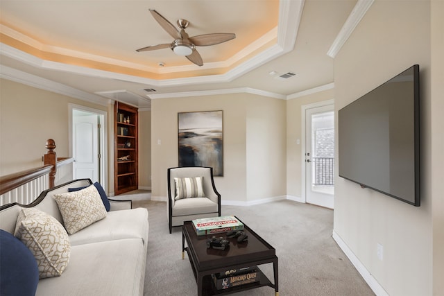 living room with light carpet, a tray ceiling, ceiling fan, and crown molding