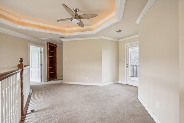 carpeted spare room featuring crown molding, a tray ceiling, and ceiling fan