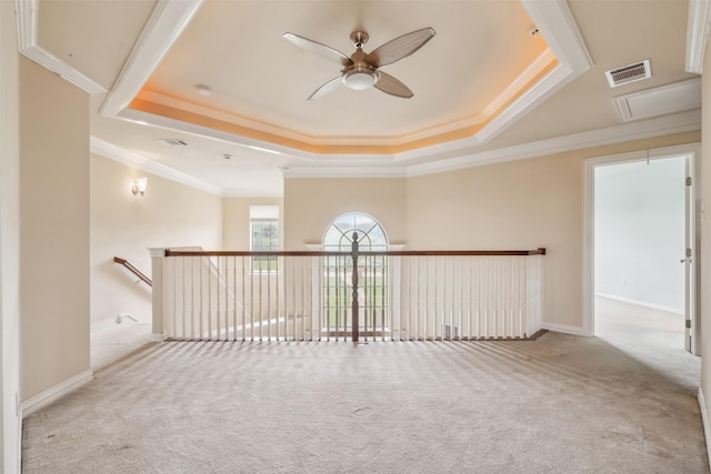 empty room with attic access, a tray ceiling, visible vents, and carpet