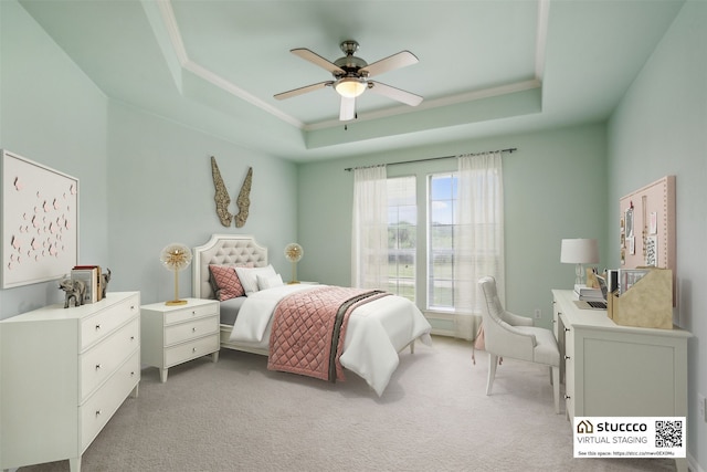 carpeted bedroom with ceiling fan and a tray ceiling