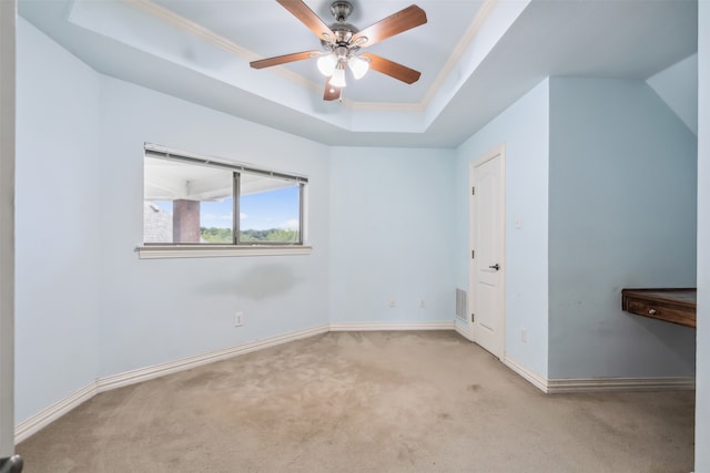 carpeted empty room featuring ceiling fan, ornamental molding, and a tray ceiling