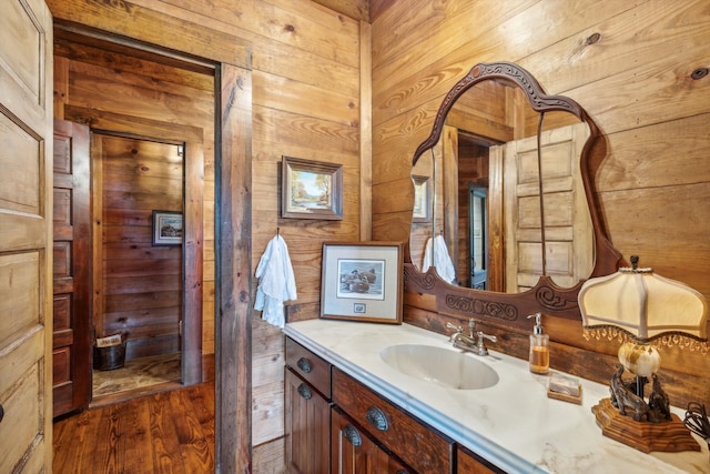 bathroom featuring wood walls, hardwood / wood-style floors, and large vanity