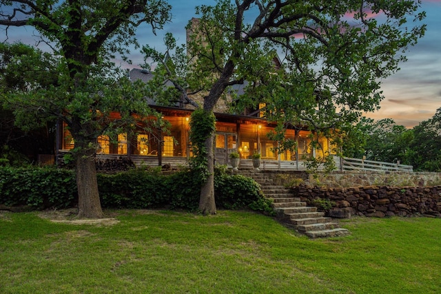 back house at dusk with a lawn