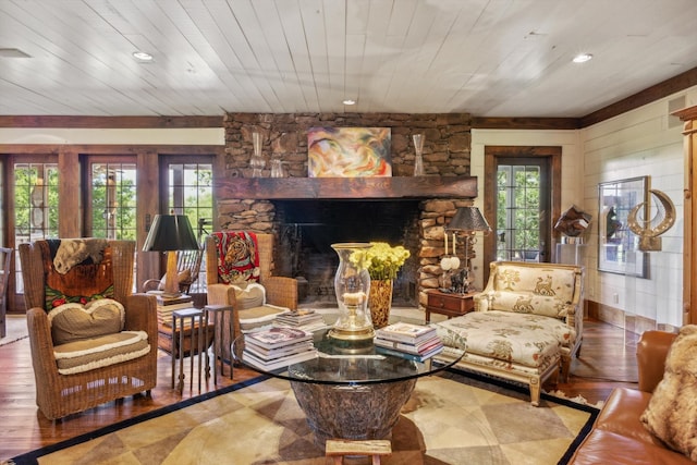 living room with hardwood / wood-style floors, a stone fireplace, and wood ceiling