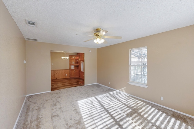 spare room featuring light carpet, a textured ceiling, and ceiling fan with notable chandelier