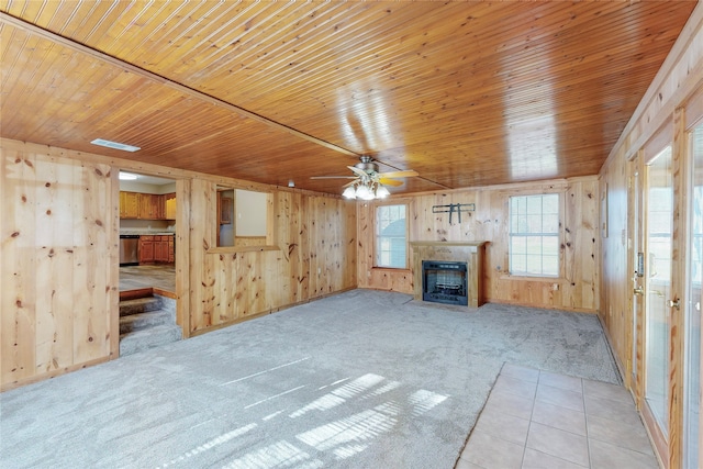 unfurnished living room with ceiling fan, light colored carpet, wooden walls, and wooden ceiling