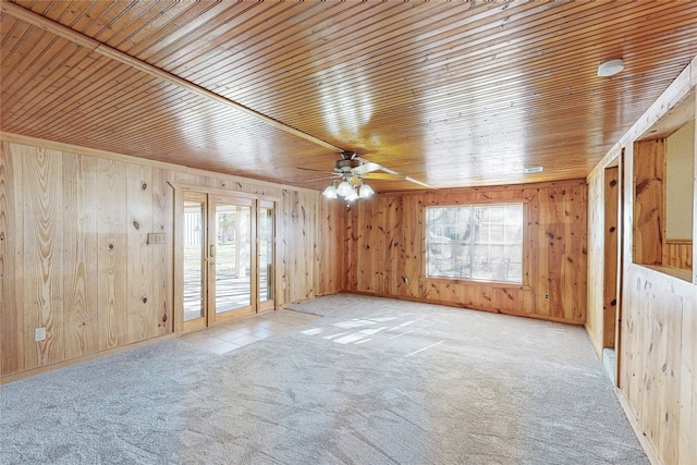 carpeted spare room with ceiling fan, wood walls, and wooden ceiling