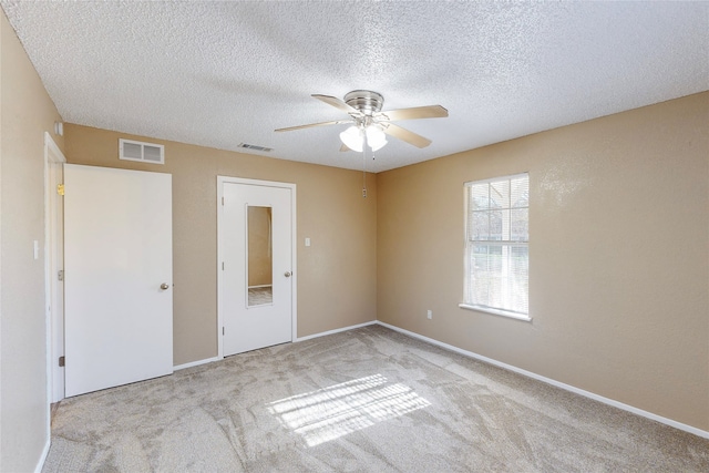 unfurnished bedroom featuring a textured ceiling, light carpet, and ceiling fan