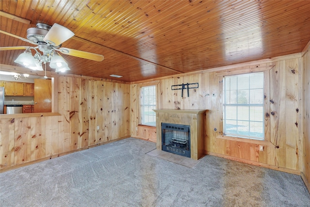 unfurnished living room with ceiling fan, wood ceiling, wooden walls, light carpet, and a fireplace