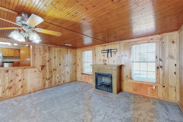 unfurnished living room featuring wooden ceiling, carpet flooring, wooden walls, and a healthy amount of sunlight