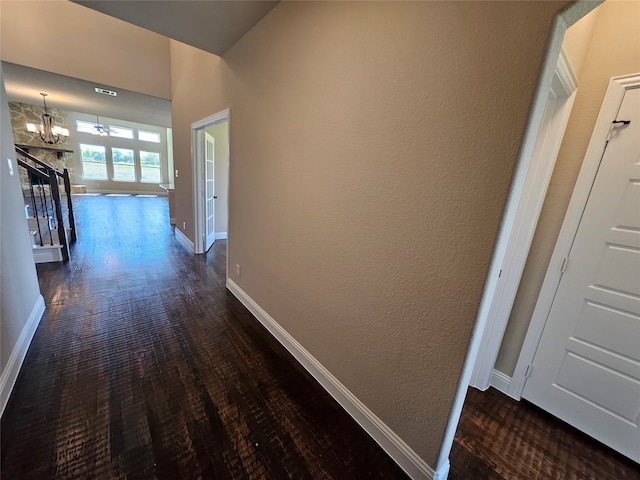 hall featuring dark wood-type flooring and a chandelier