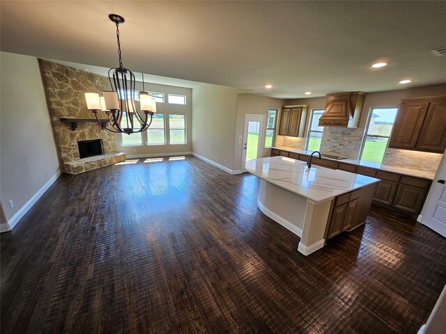 kitchen featuring tasteful backsplash, a fireplace, pendant lighting, a center island, and a notable chandelier