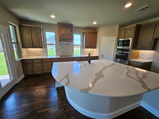 kitchen featuring appliances with stainless steel finishes, a center island with sink, sink, and decorative backsplash