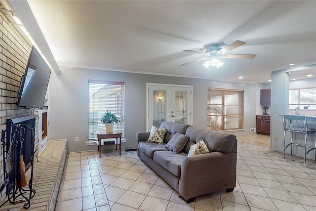 tiled living room with ceiling fan, crown molding, and a fireplace