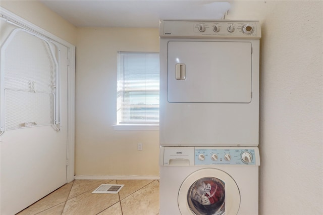 clothes washing area featuring light tile patterned floors and stacked washer and clothes dryer