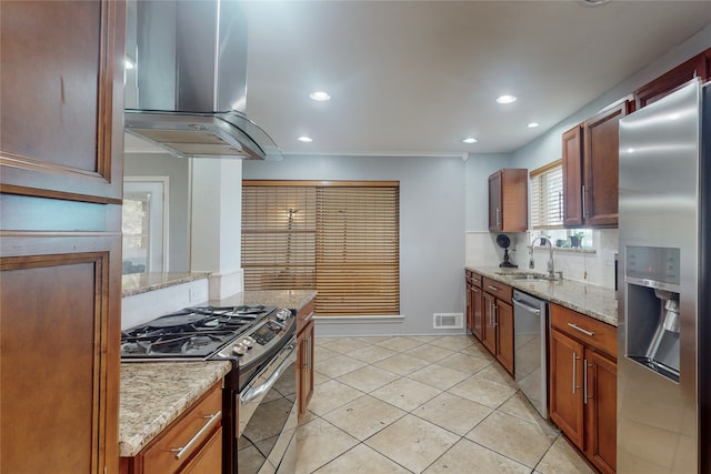 kitchen featuring wall chimney range hood, sink, light tile patterned flooring, appliances with stainless steel finishes, and light stone counters