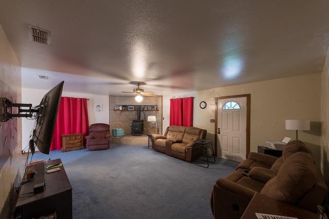 living room with carpet flooring, ceiling fan, a wood stove, and a textured ceiling