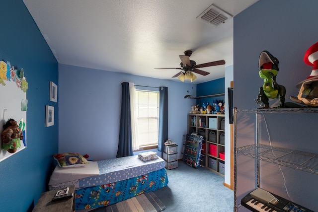 carpeted bedroom featuring a textured ceiling and ceiling fan