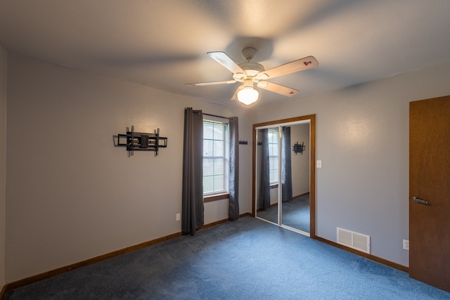 unfurnished bedroom with dark carpet, ceiling fan, and a closet