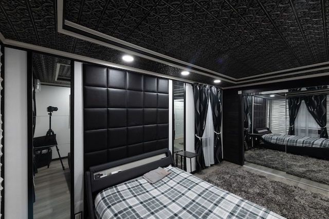 bedroom featuring crown molding, hardwood / wood-style floors, and a tray ceiling