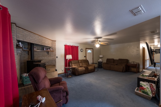 carpeted living room with a wood stove, ceiling fan, and a textured ceiling