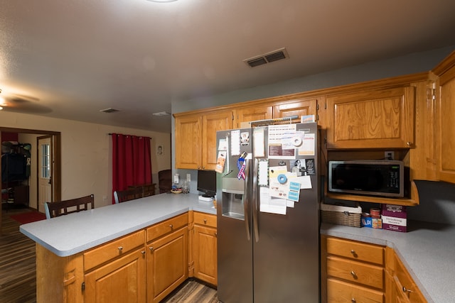 kitchen featuring light hardwood / wood-style flooring, stainless steel appliances, kitchen peninsula, ceiling fan, and a kitchen bar