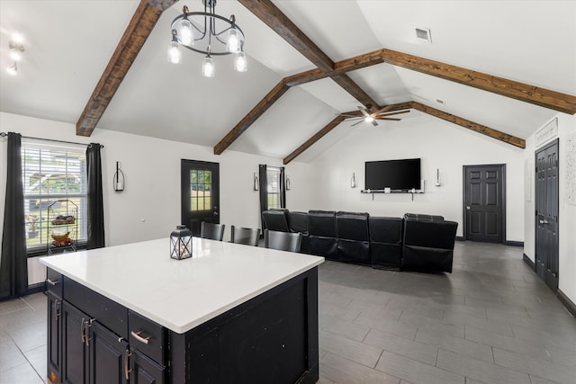 kitchen with ceiling fan with notable chandelier, lofted ceiling with beams, a center island, and tile flooring