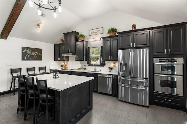 kitchen featuring a center island, lofted ceiling with beams, backsplash, stainless steel appliances, and sink