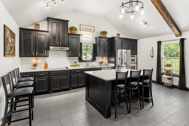 kitchen with beamed ceiling, a breakfast bar area, a wealth of natural light, and a center island