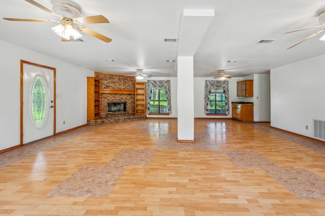 unfurnished living room featuring a brick fireplace, ceiling fan, and light wood-type flooring